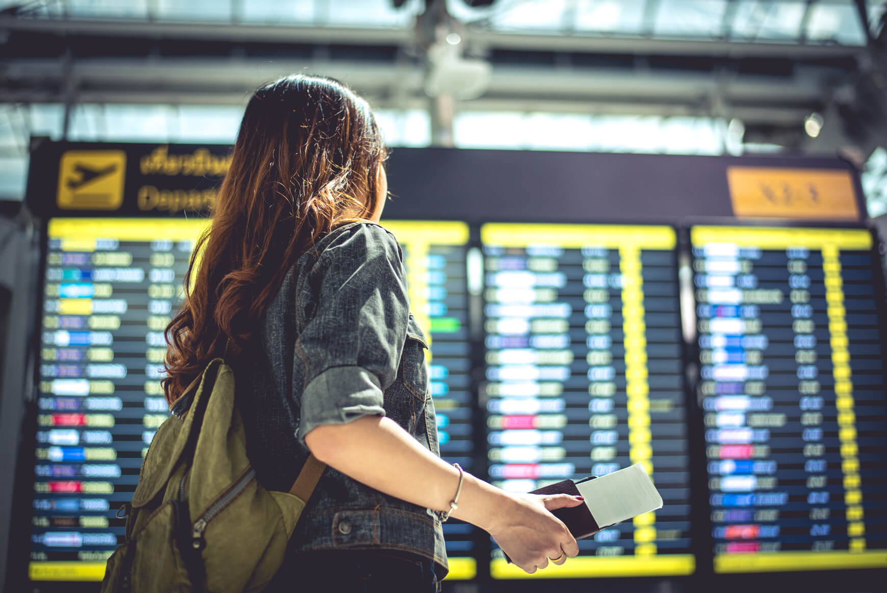 eine Frau steht vor einer Anzeigentafel am Flughafen